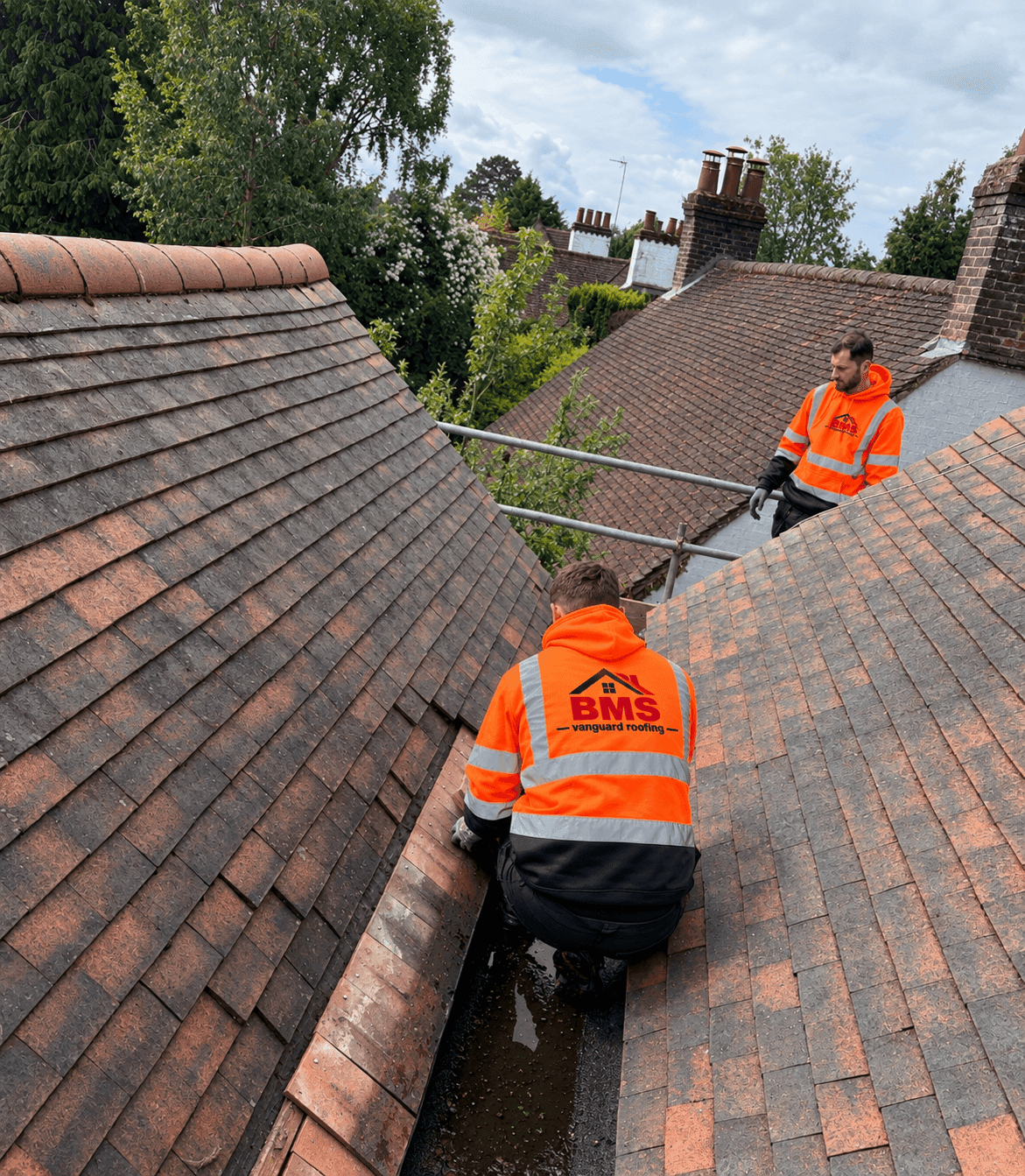 BMS Vanguard roofers working on a tiled roof in hi-vis jackets