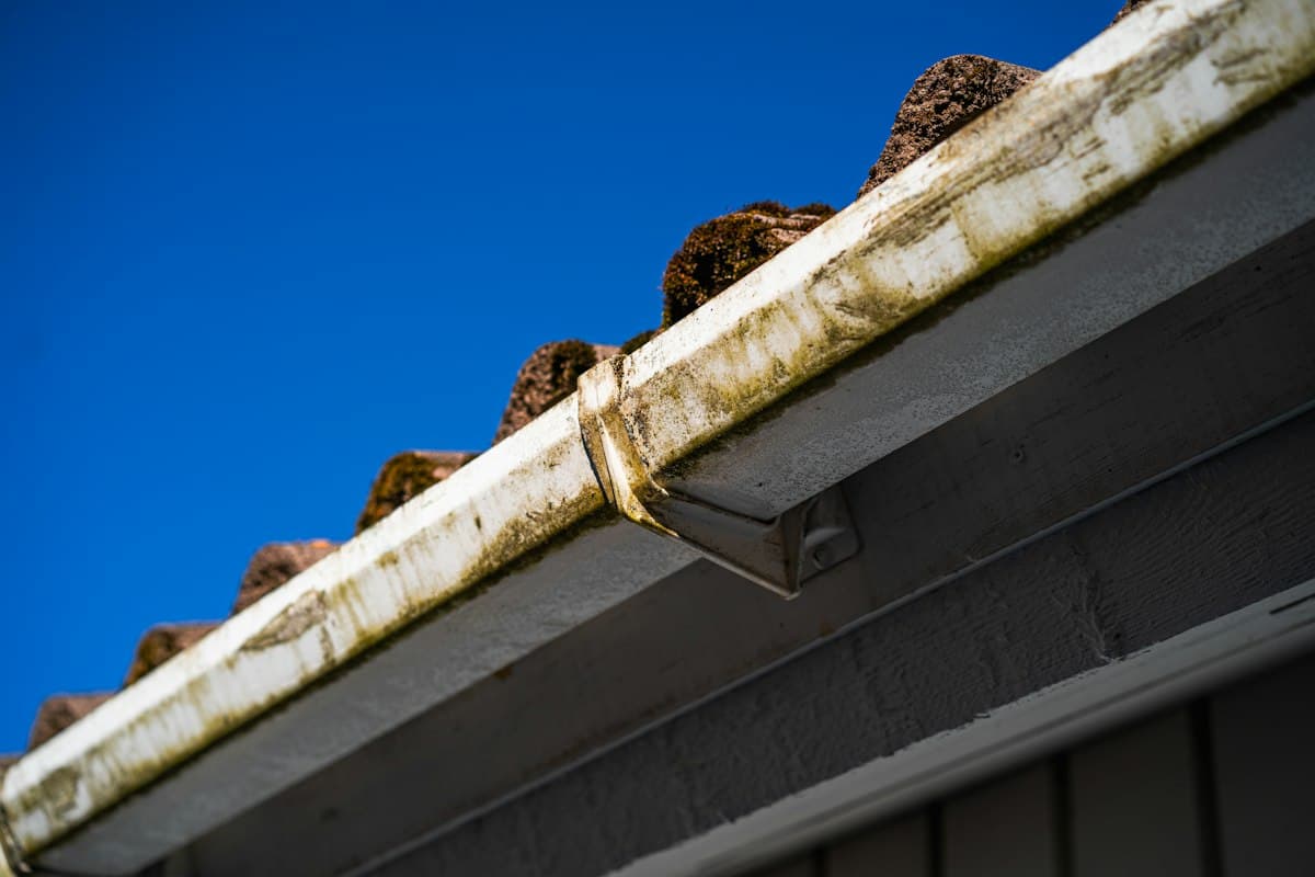 Worn gutter held on brackets below a tiled roof