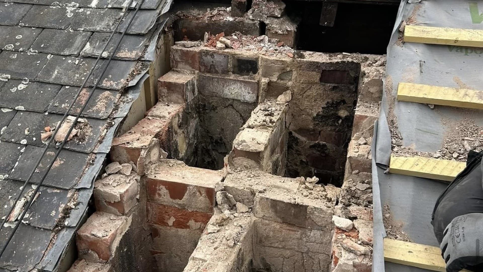 Brick chimney stack being repaired on a slate roof