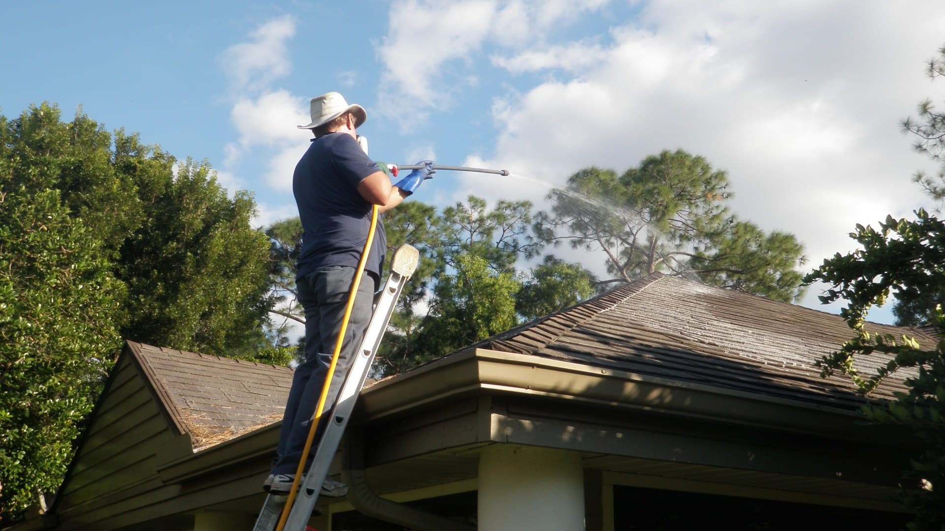 Roof being pressure washed to remove moss and dirt